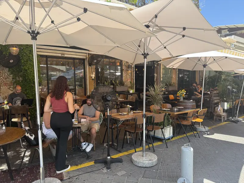 המרפסת תחת שמשיות לבנות, אורחים בשולחנות